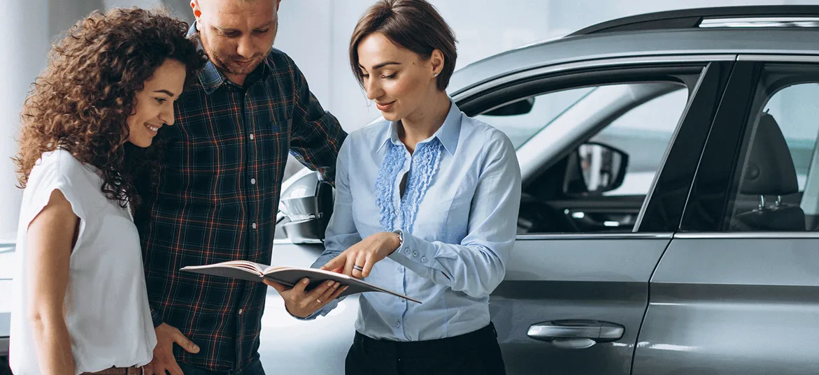 A couple talking through car finance options with a specialist at a dealership